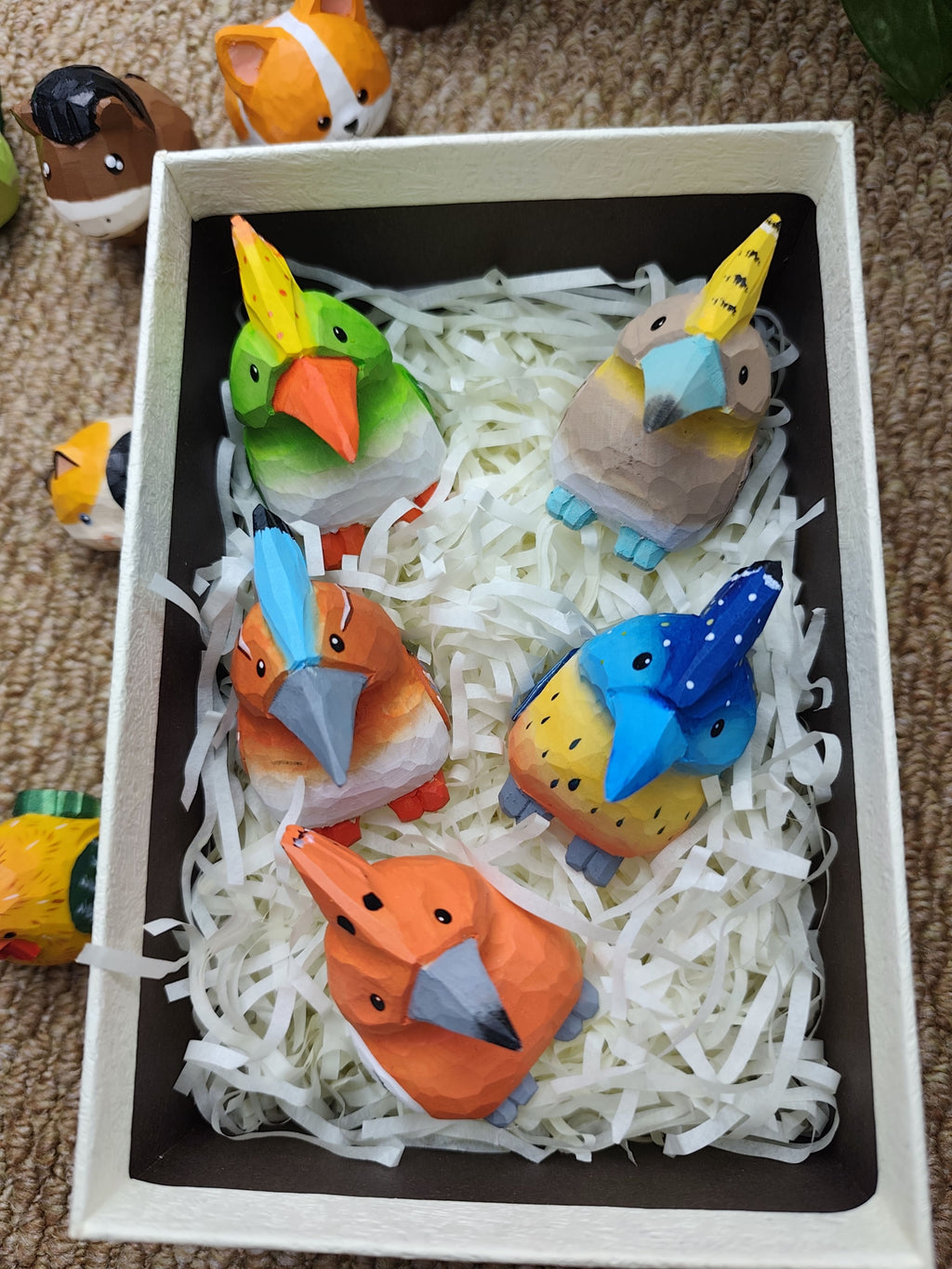 Five hand-carved and hand-painted wooden hoopoe birds in vibrant colors including green, orange, and blue, nestled in a gift box.