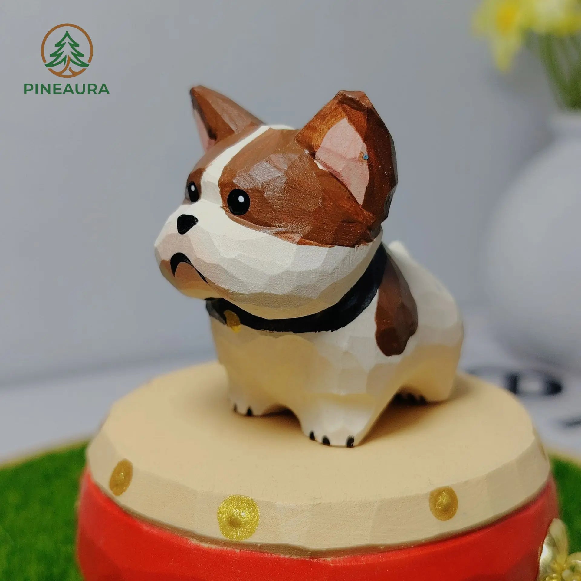 Adorable low-poly brown and white French Bulldog figurine with black collar, standing on a red music box by PINEAURA