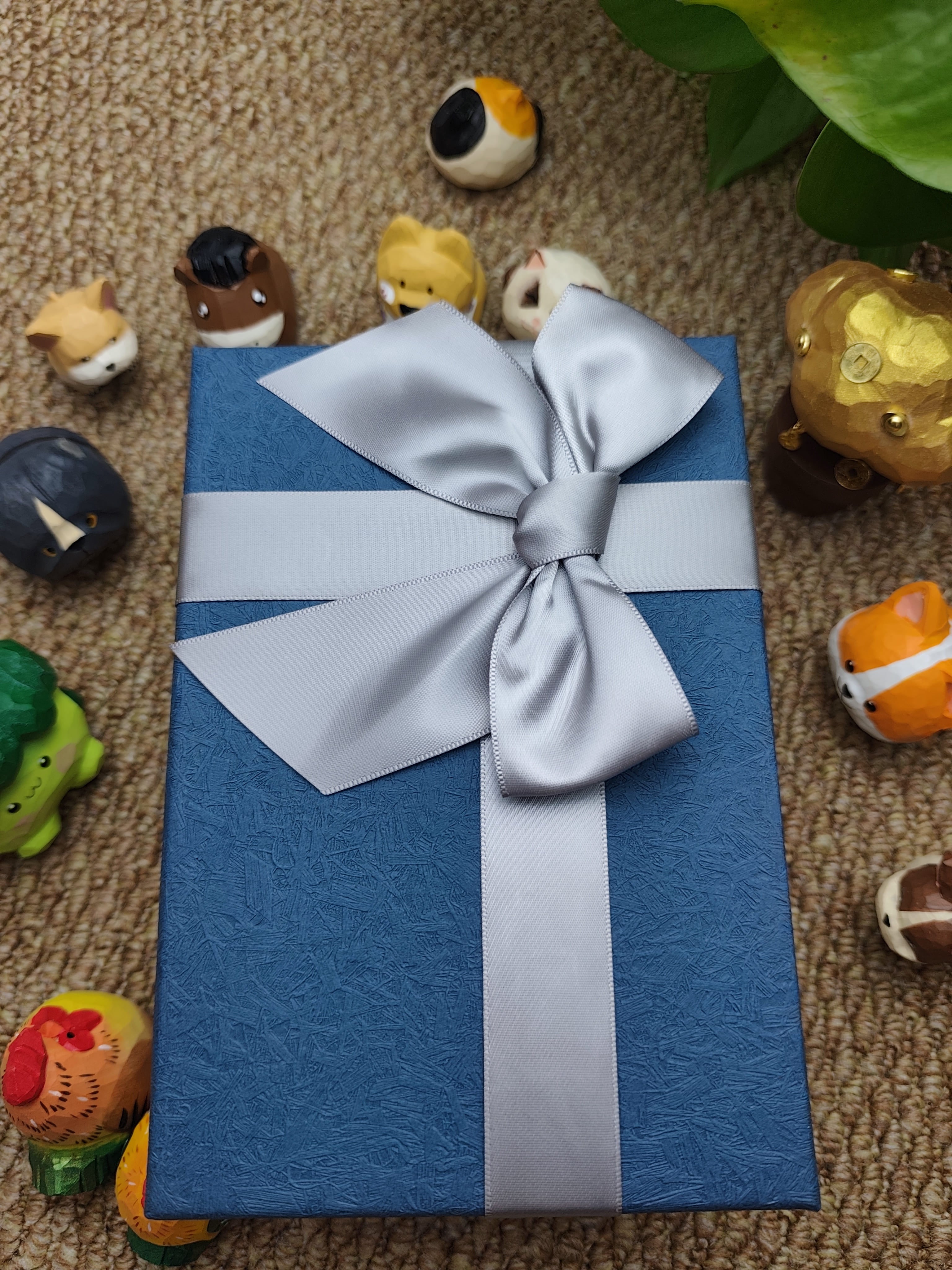 A premium blue textured gift box tied with a silver satin ribbon, perfect for bird lovers and collectors.
